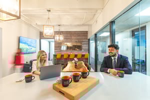 Two people sitting at the coffee bar, working and talking. 